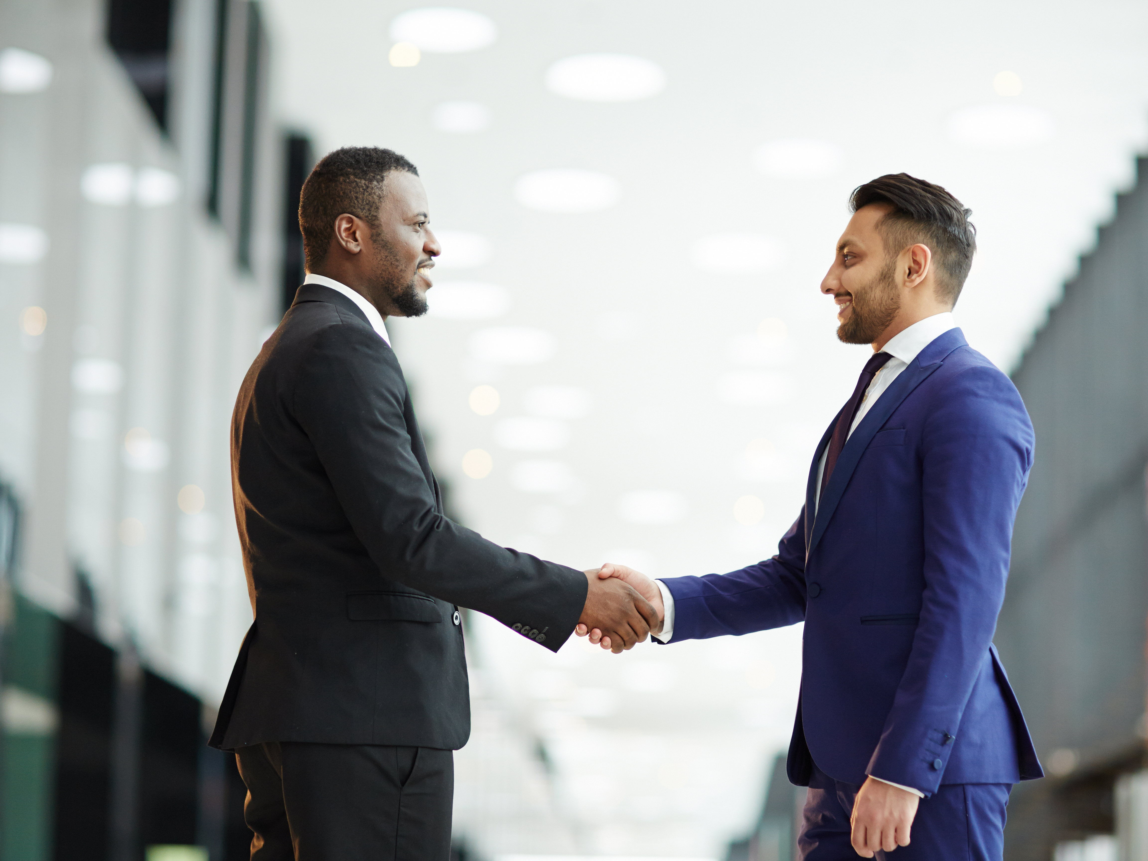 Two business professionals shaking hands in a modern office