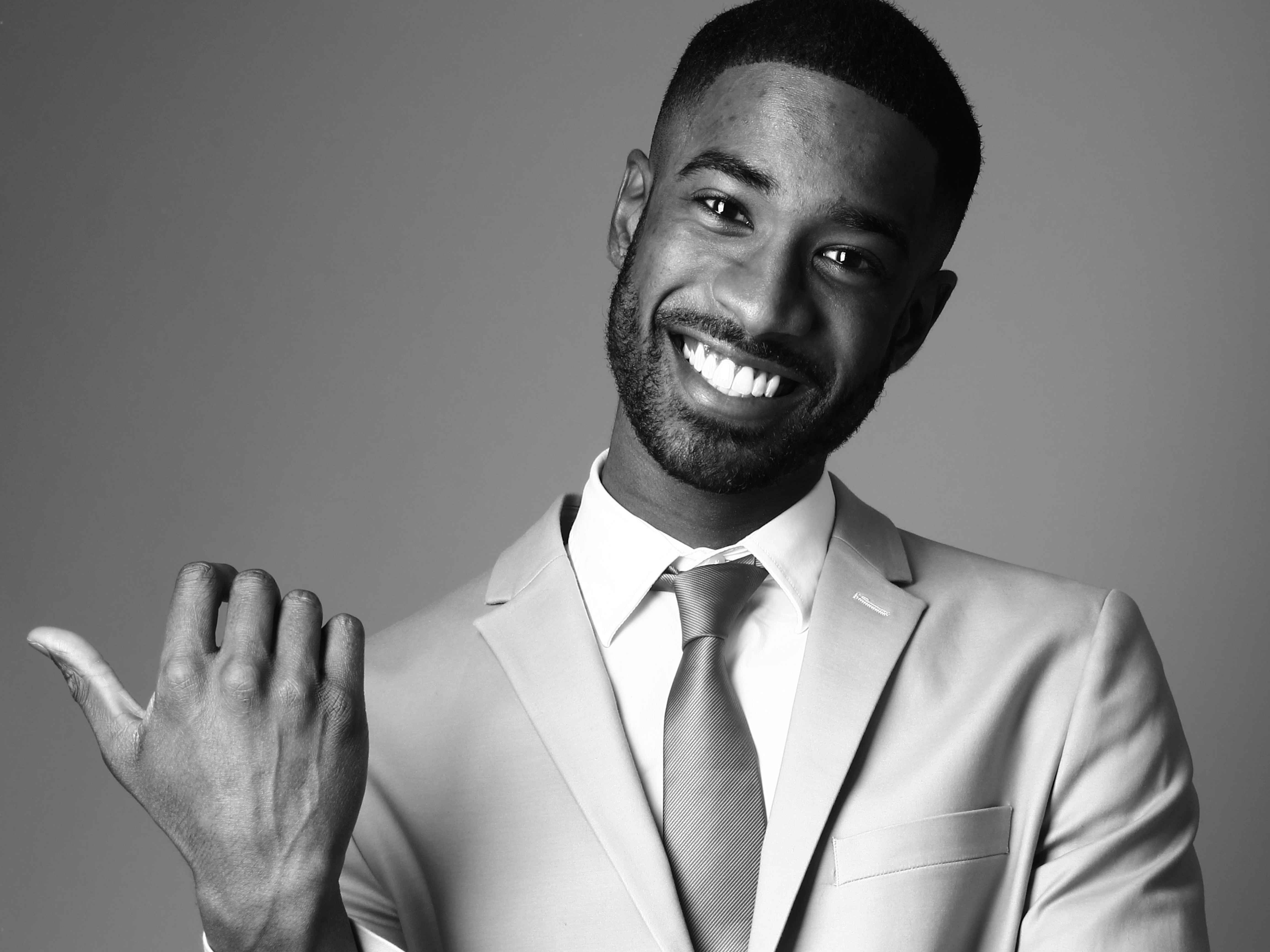 Approachable Black host in a suit with a welcoming gesture