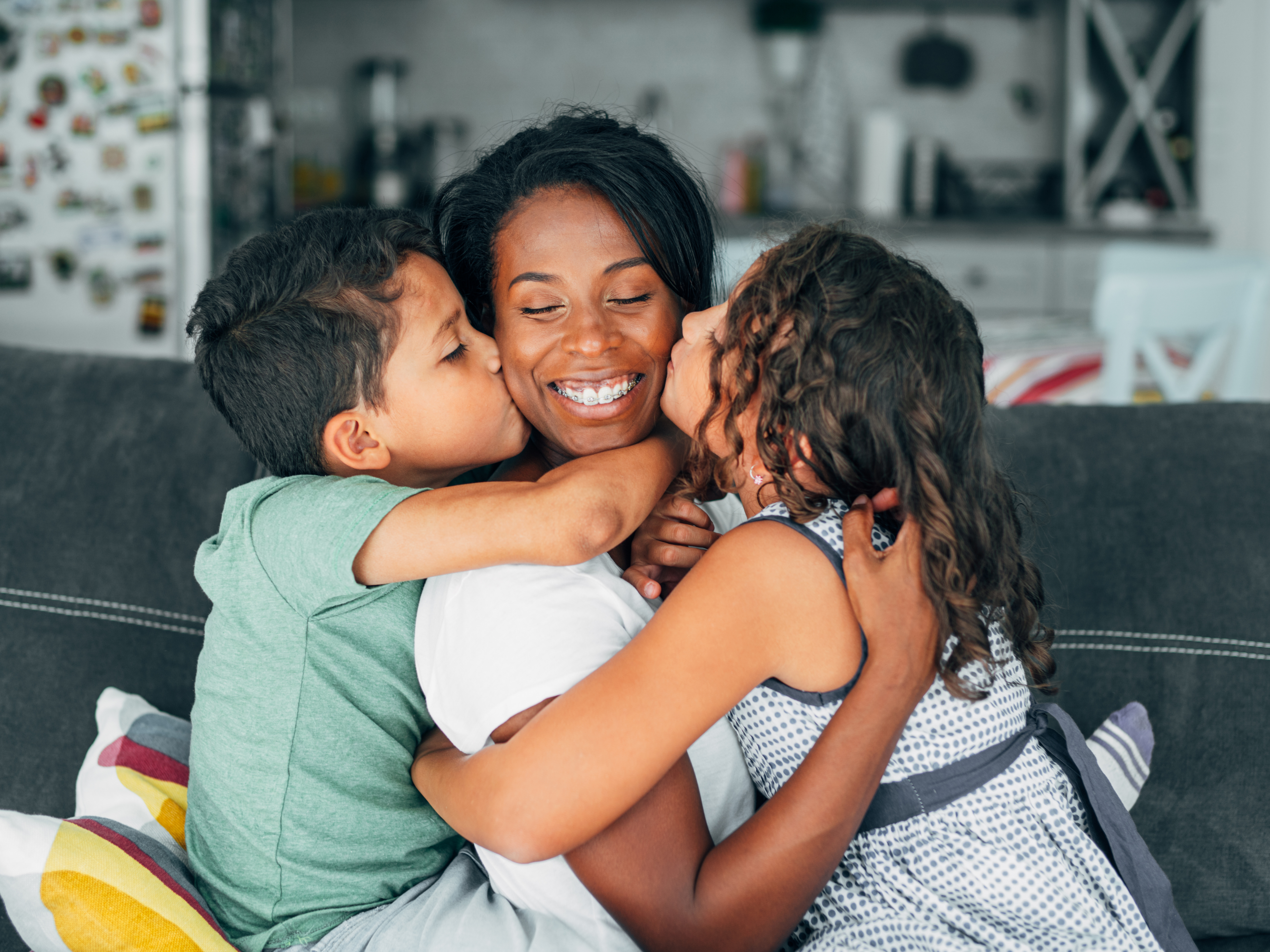 Mother embraced by her children on a living room sofa