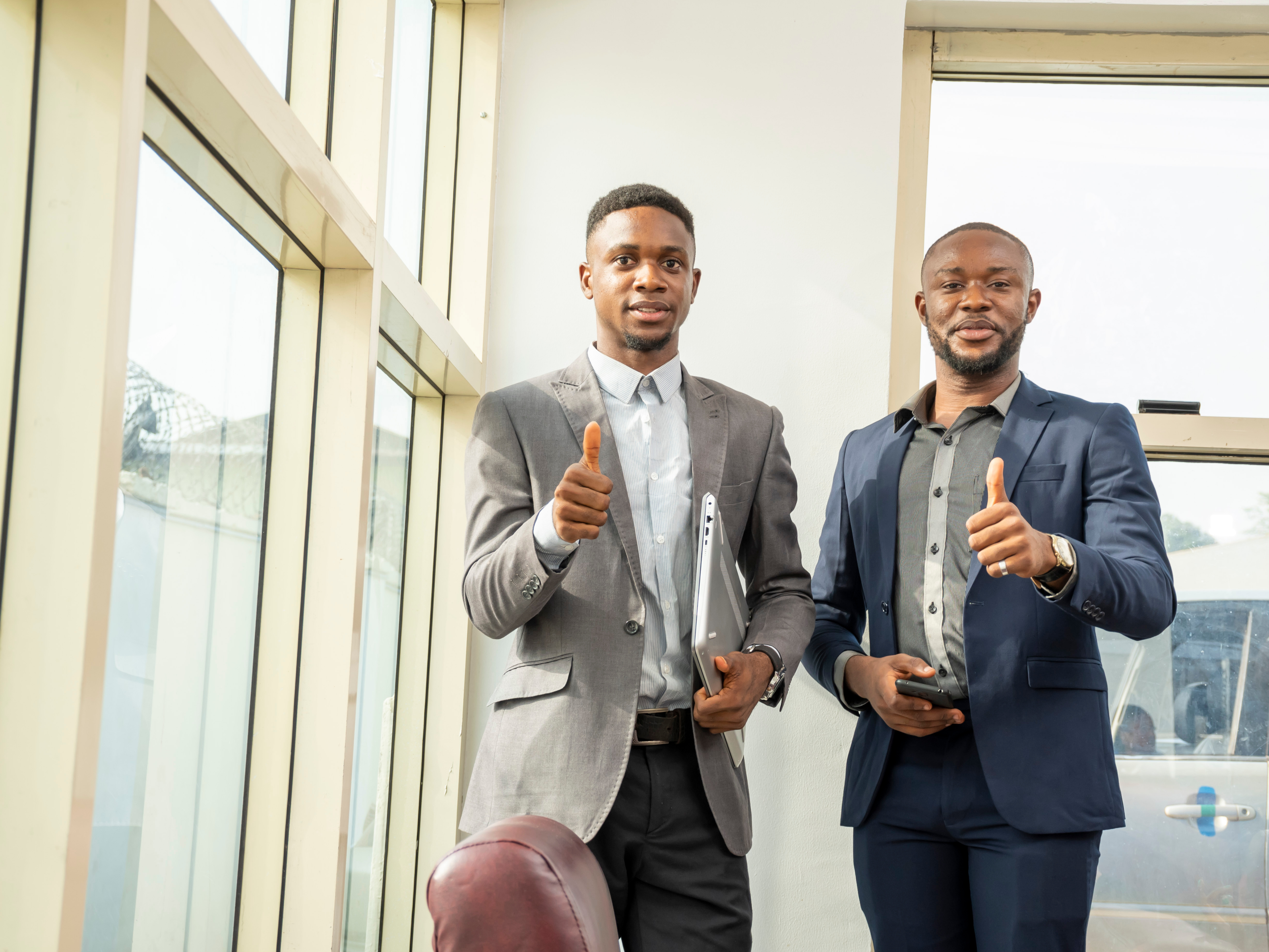 Two successful Black business owners giving a thumbs up in a bright office