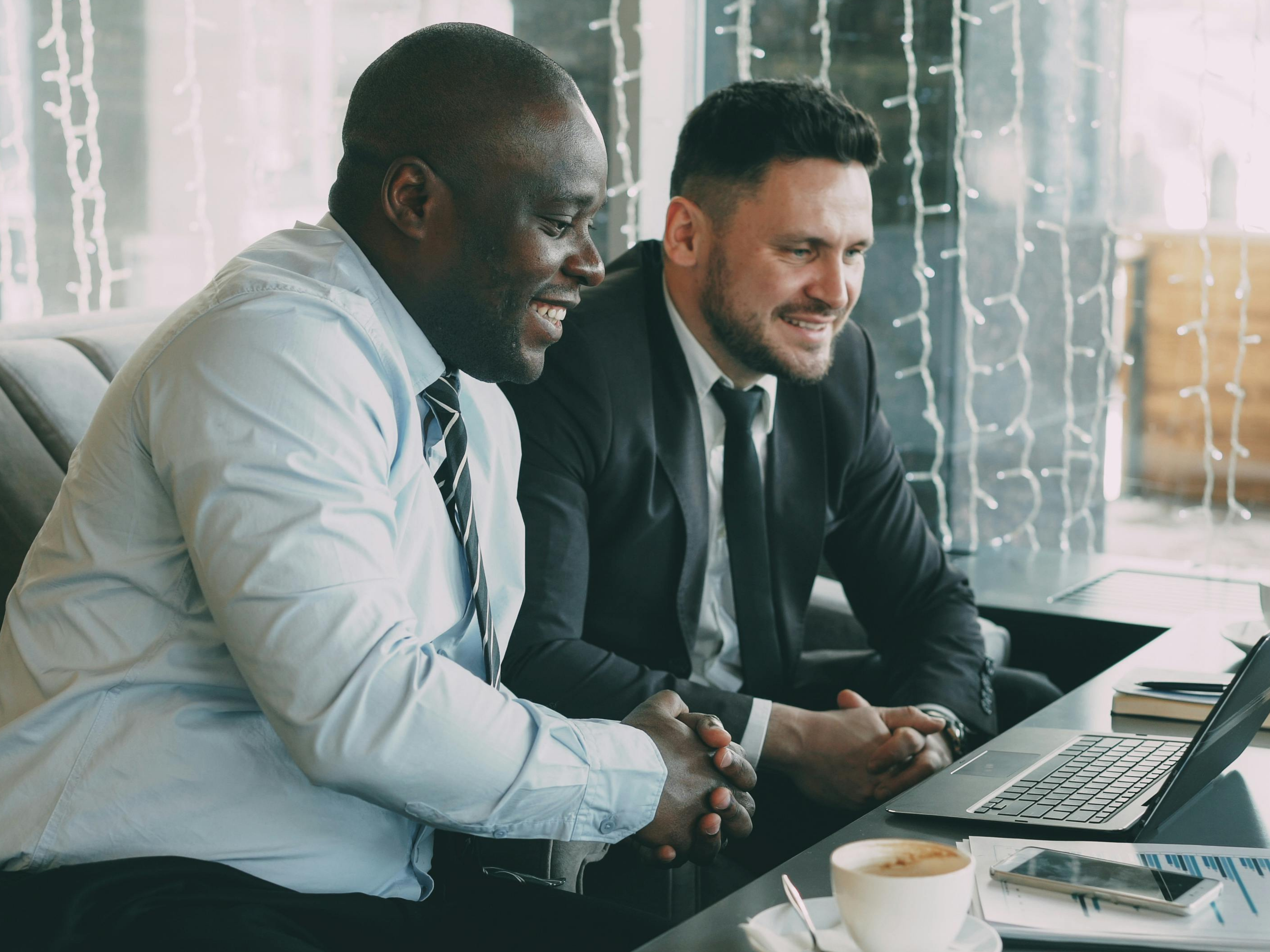 Business partners reviewing data on a laptop over coffee